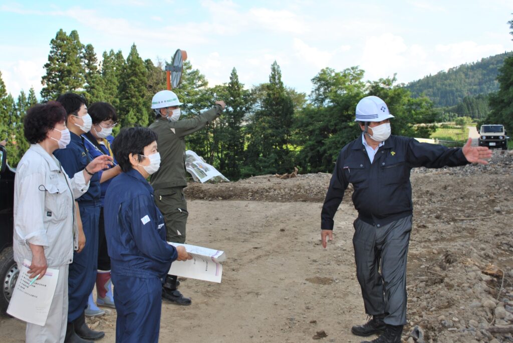 内谷重治市長（右端）から土砂災害の現場で設営を受ける一行（8月6日、長井市）